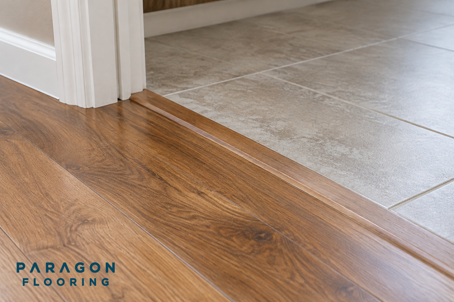 A close-up of a door threshold showing where new hardwood flooring meets another flooring type with a transition strip.