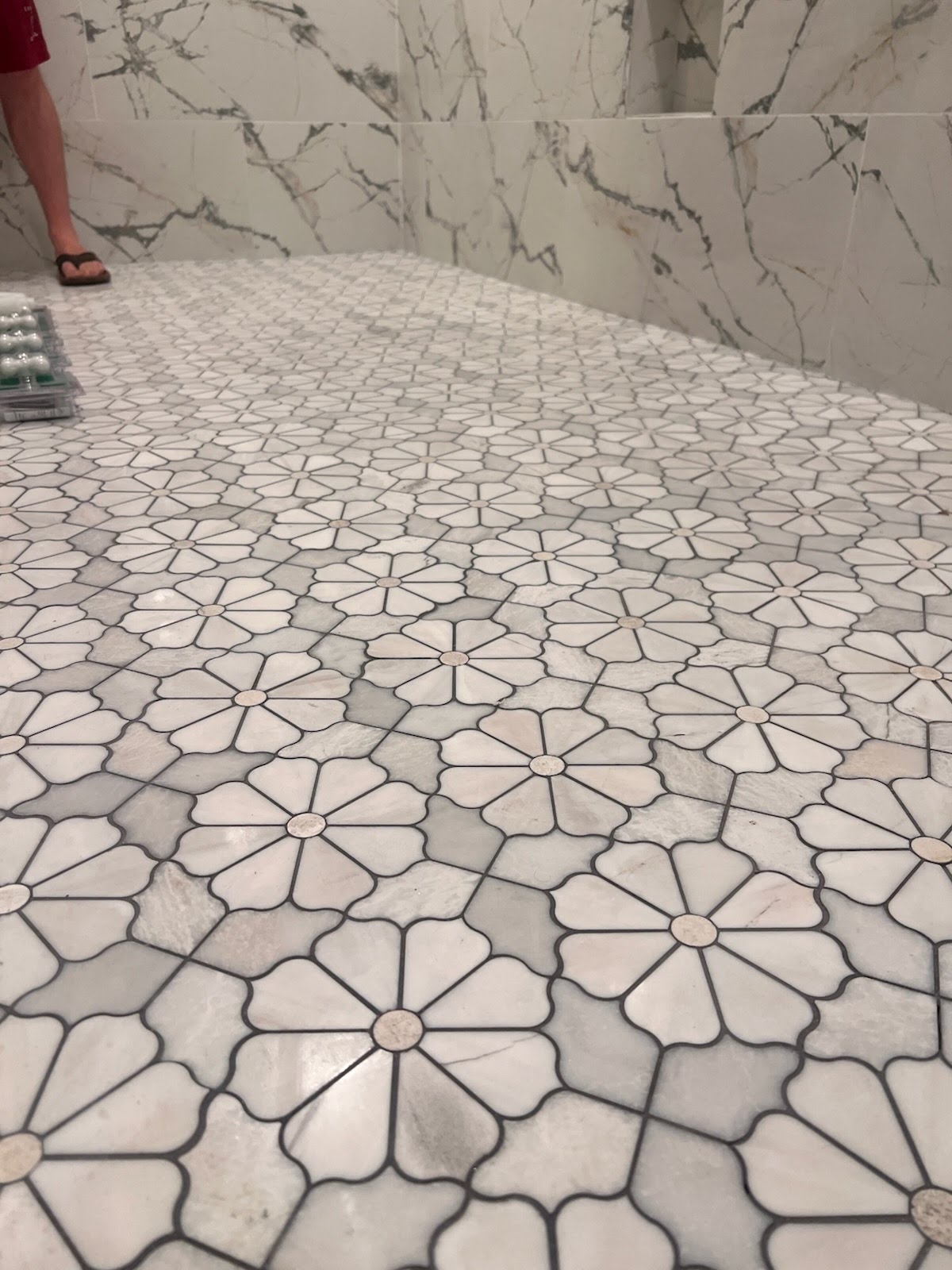 Close view of white floral mosaic floor tile with gray insets and dark grout lines
