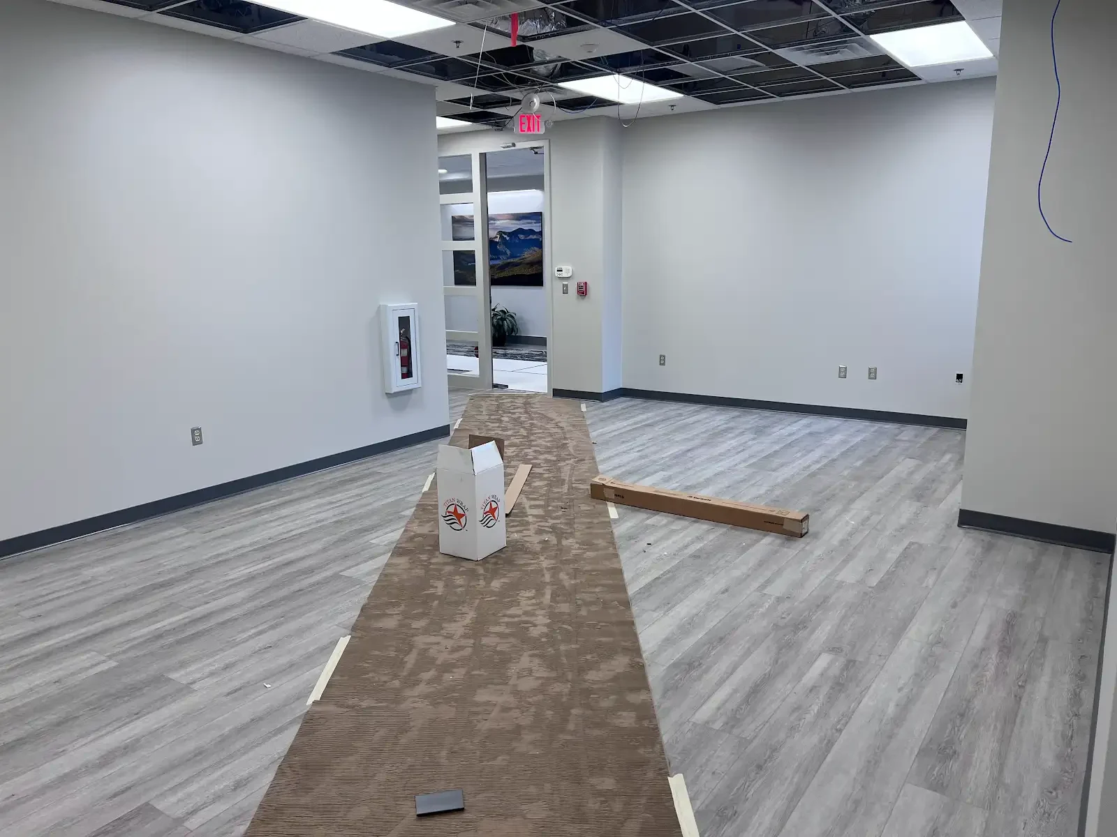 Gray plank flooring installation in progress with exposed substrate and materials